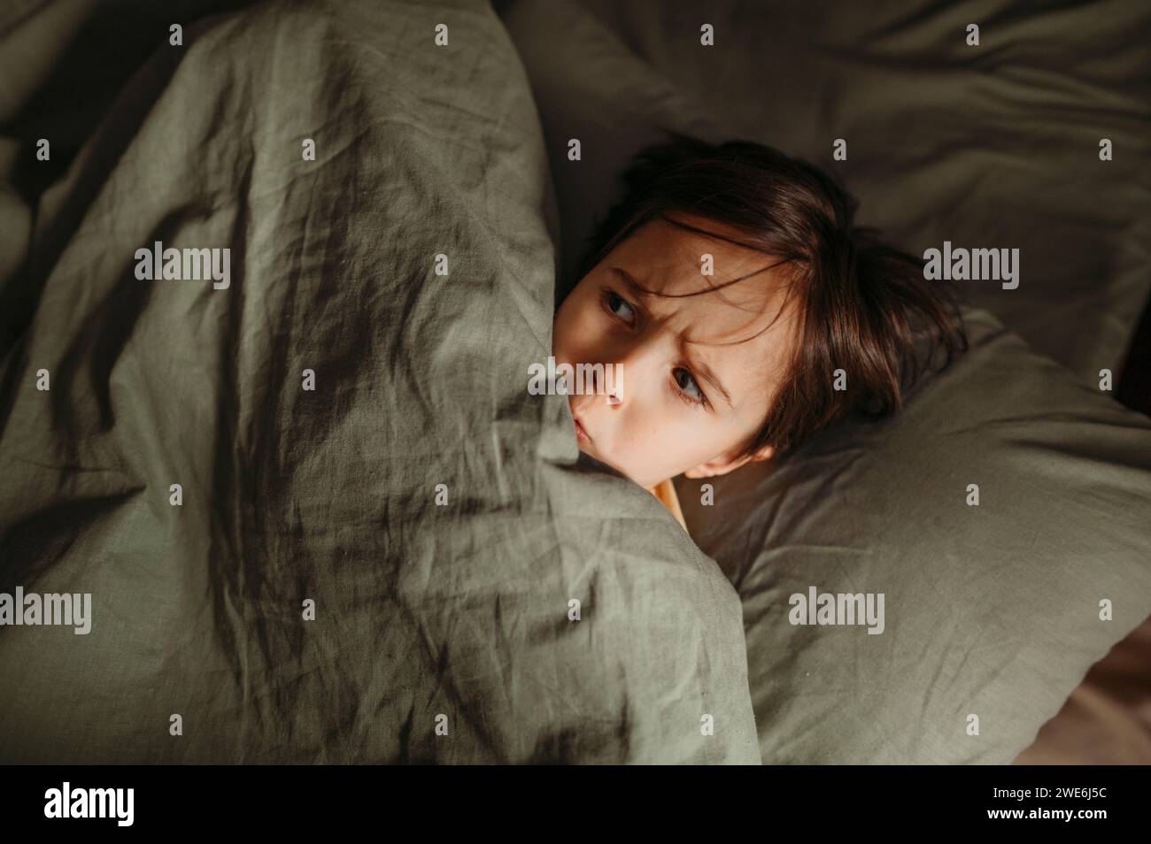 Verängstigter Junge, der sich zu Hause unter der Decke versteckt Stockfoto