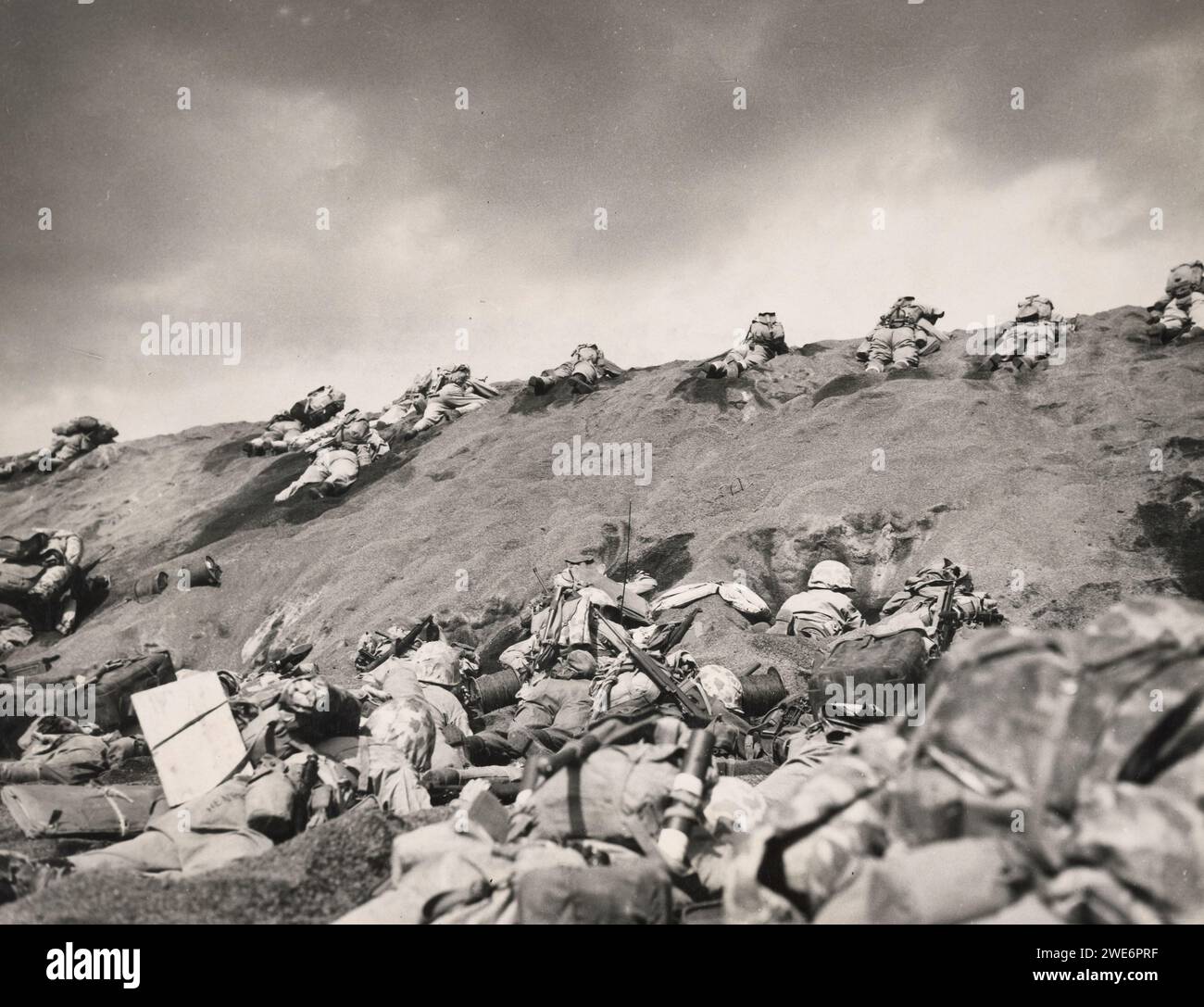 Angesichts des verwelkenden feindlichen Feuers arbeiten sich die Invasoren der Fifth Division von Iwo Jima den Hang von Red Beach One hinauf in Richtung Suribachi Yama, vollständig versteckt im linken Hintergrund durch den Rauch der Schlacht - Iwo Jima 1945 Stockfoto