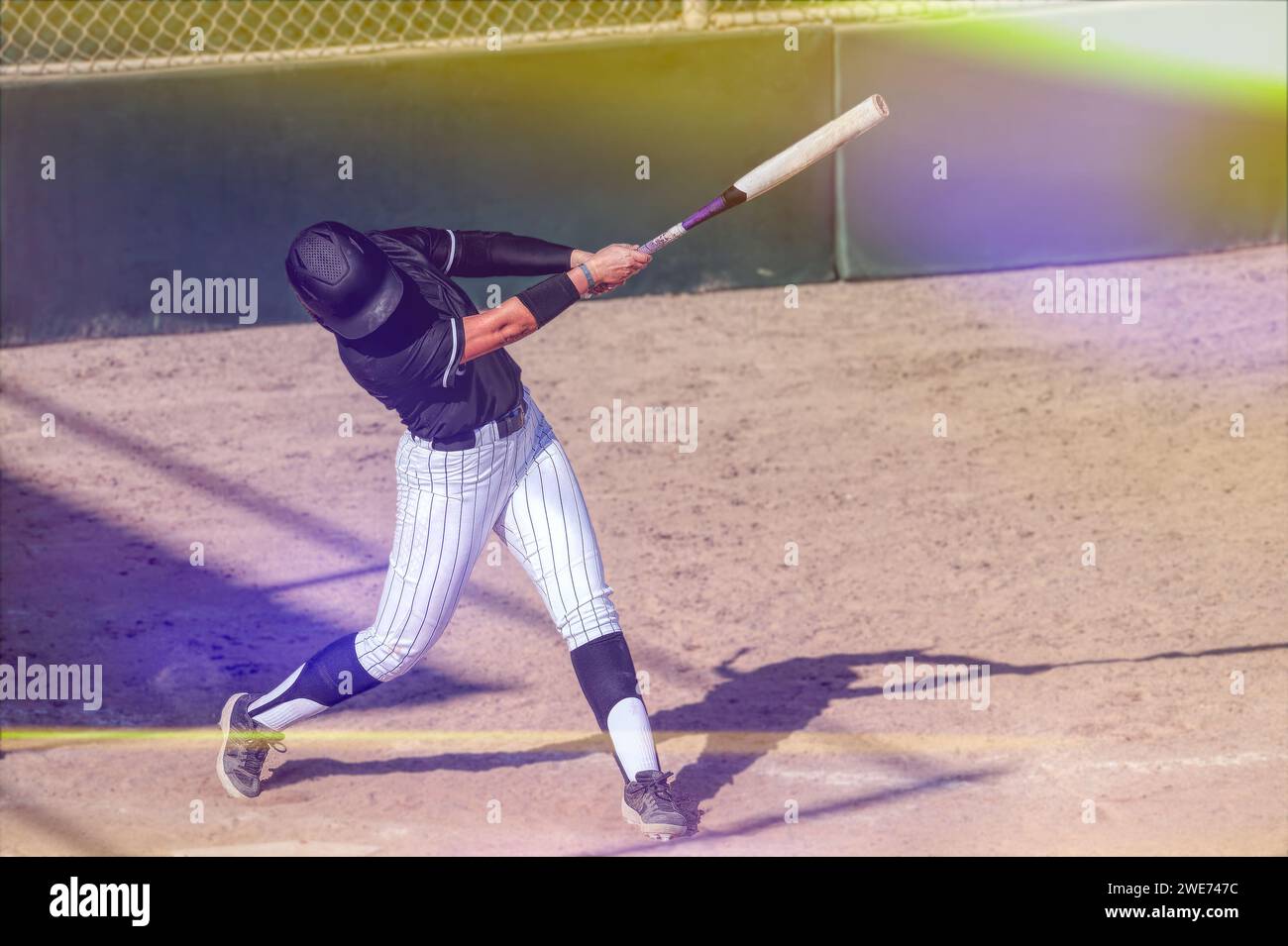 Ein Baseball-Softball-Spieler schwingt die Fledermaus und schlägt den Ball mit Flare Stockfoto