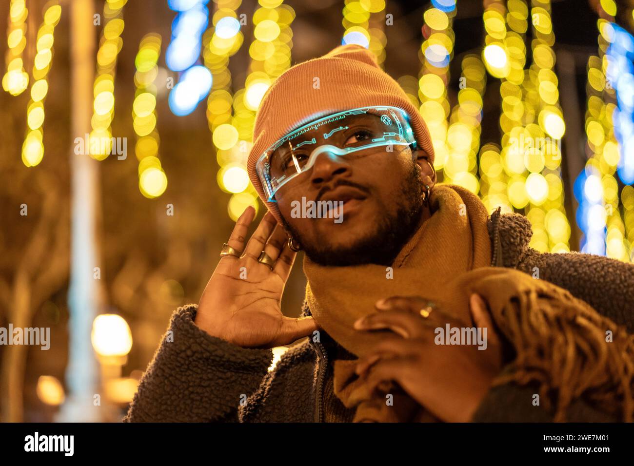 Afrikanischer Mann, der nachts in der Stadt mit einer intelligenten Brille zuhört Stockfoto