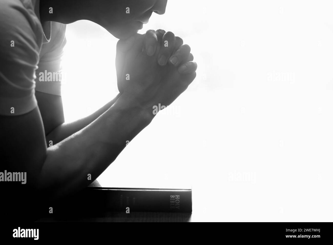 Heiliges Bibelbuch und christliche Silhouette beten und anbeten, Religion, glaube und Glaubenshintergrund Stockfoto