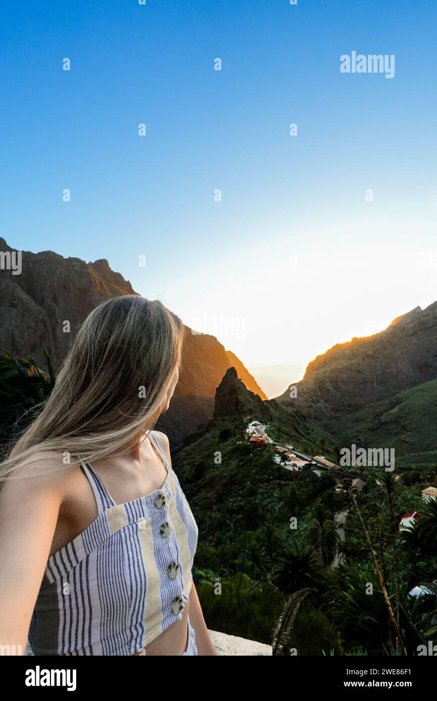 Eine Frau steht triumphierend auf einem Berggipfel und genießt den atemberaubenden Blick auf das Masca-Tal auf Teneriffa. Stockfoto