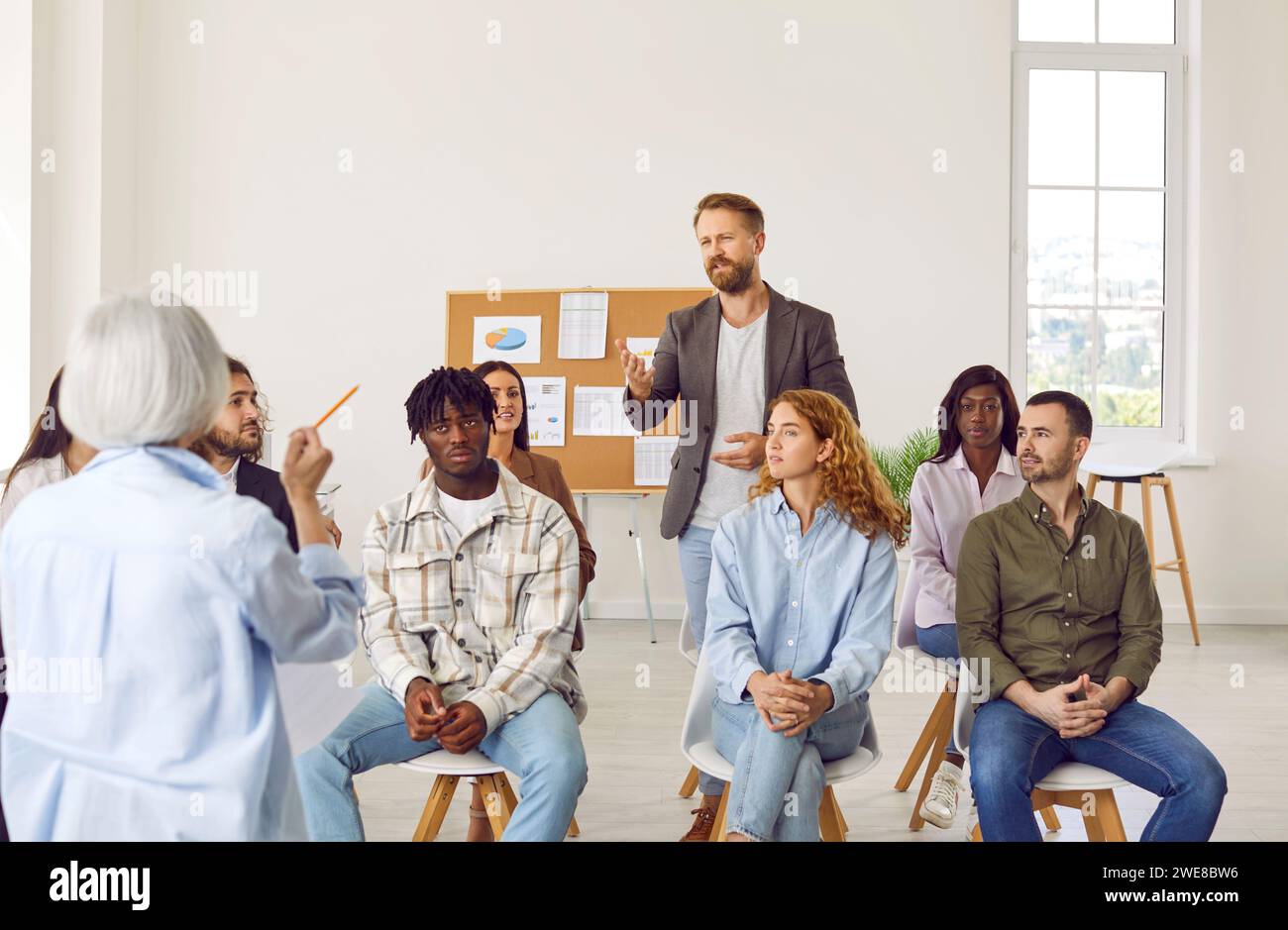 Business Coach, der während einer Besprechung im Büro mit einem unterschiedlichen Publikum diskutiert Stockfoto