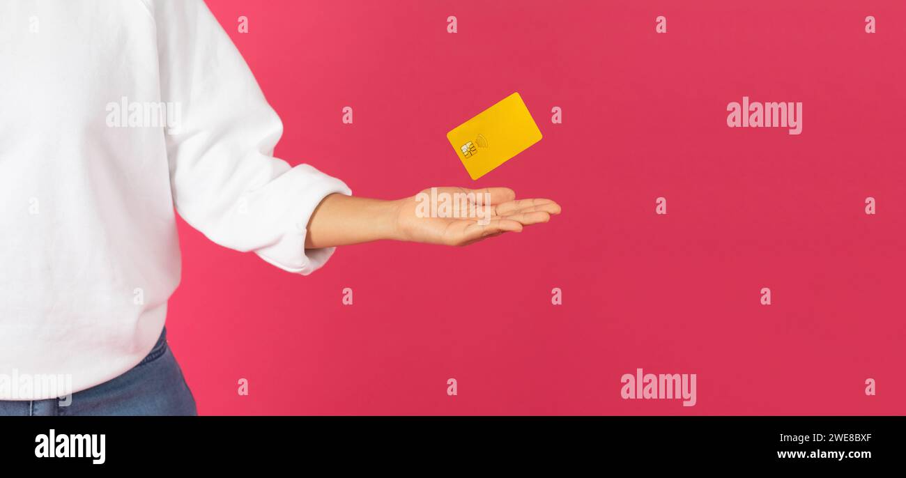 Magical Finance. Eine junge Frau, die gelbe Kreditkarte mit ihrer Handfläche schweben lässt Stockfoto