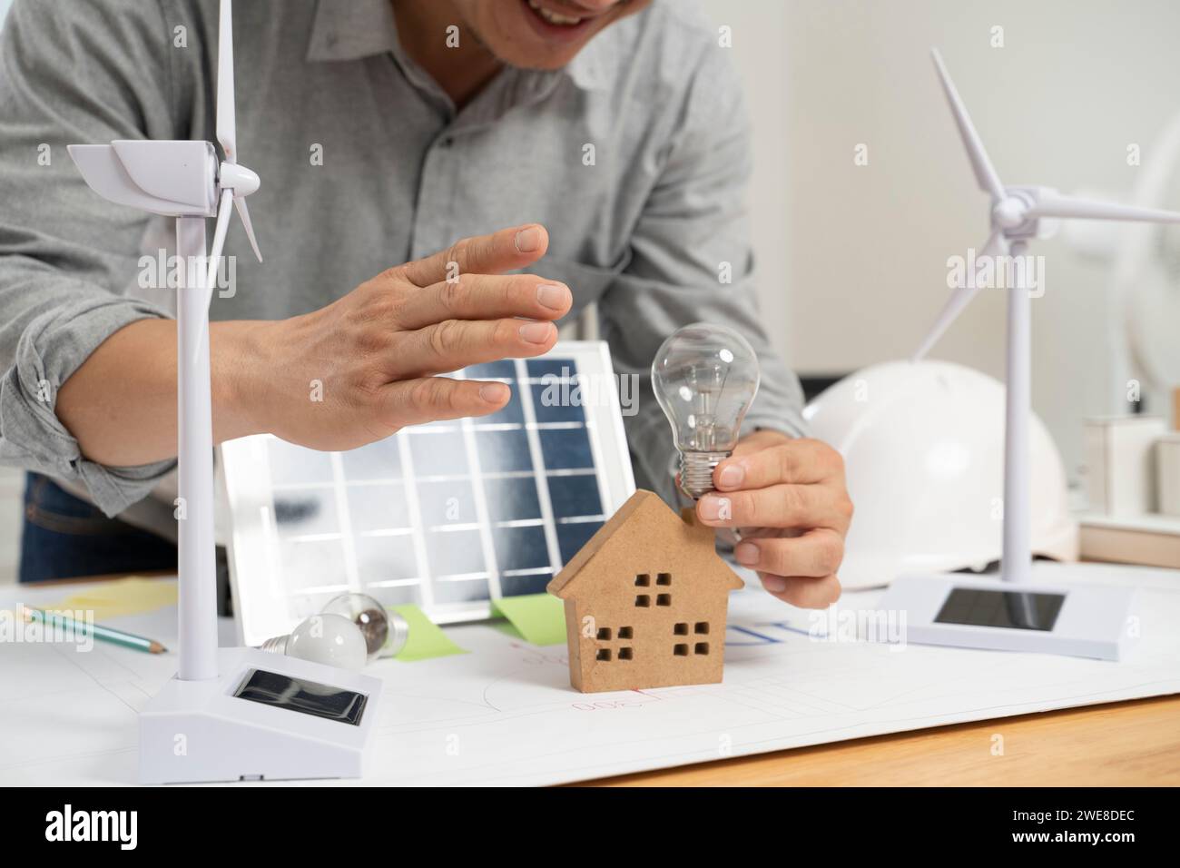Geschäftsmann hält Solarpaneele und Glühbirnen im Büro. Stockfoto