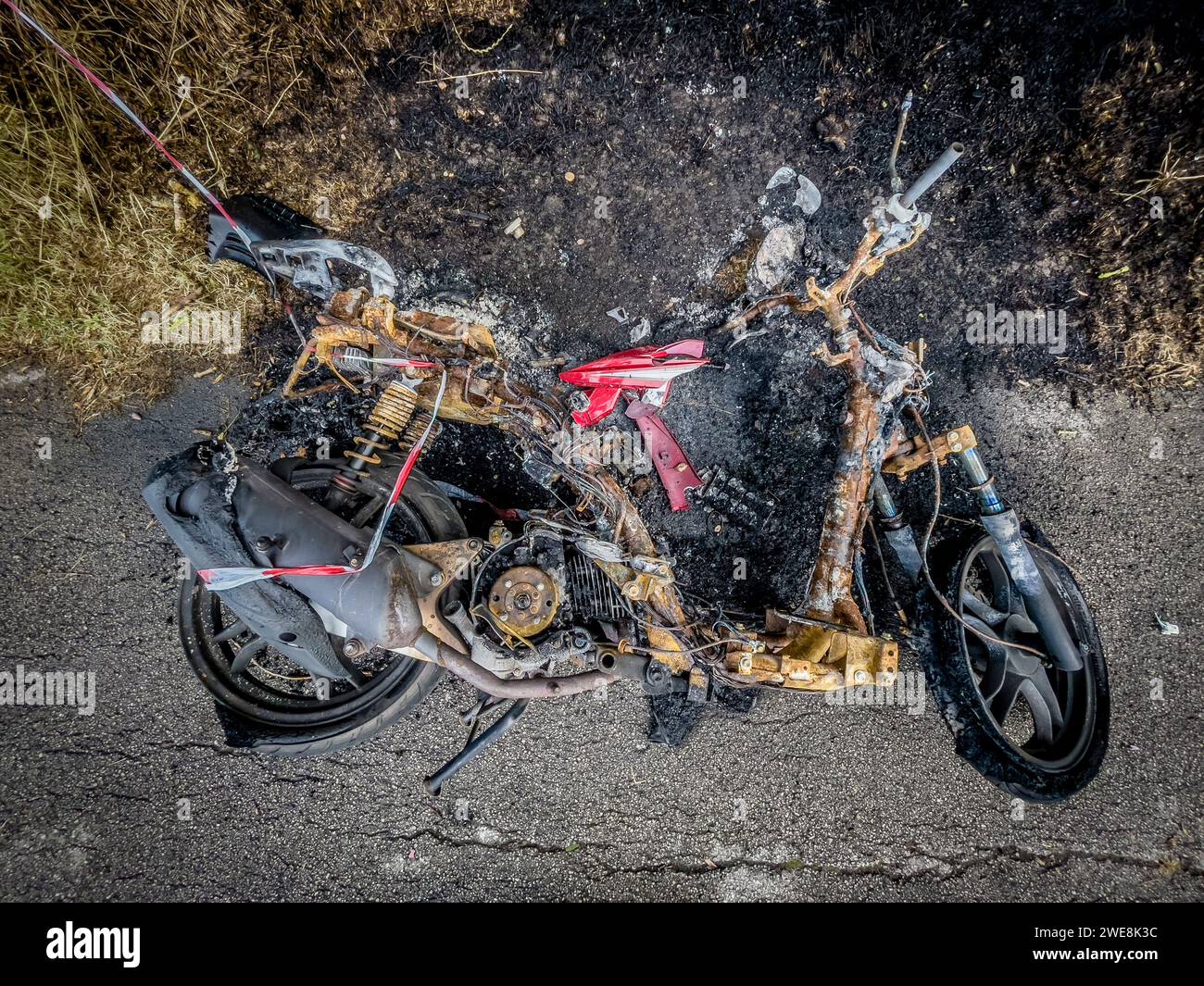 Ausgebranntes gestohlenes Motorrad am Straßenrand. Stockfoto