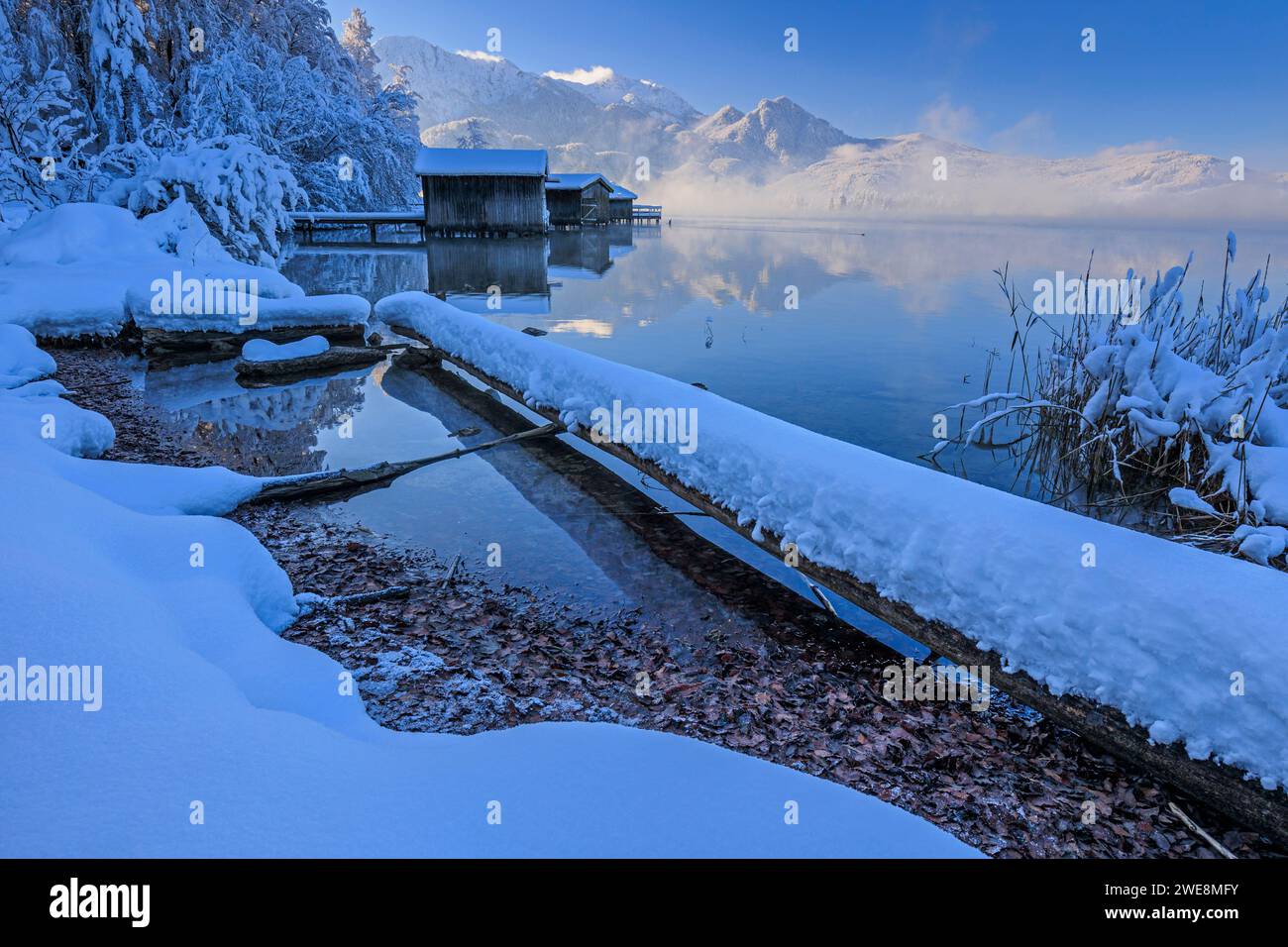 Bootshäuser, Spiegelbild der Berge im See, Winter, Schnee, Sonne, Kochelsee, Oberbayern, Bayern, Deutschland, Europa Stockfoto