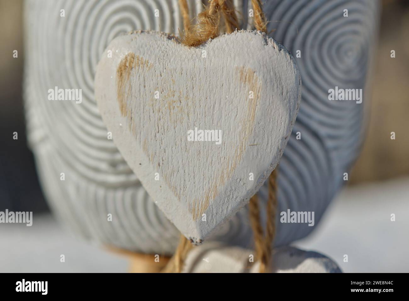 Nahaufnahme auf weißem hölzernem Herz, gehalten von Schnüren vor dekorativem Blumentopf - valentinstag Stockfoto