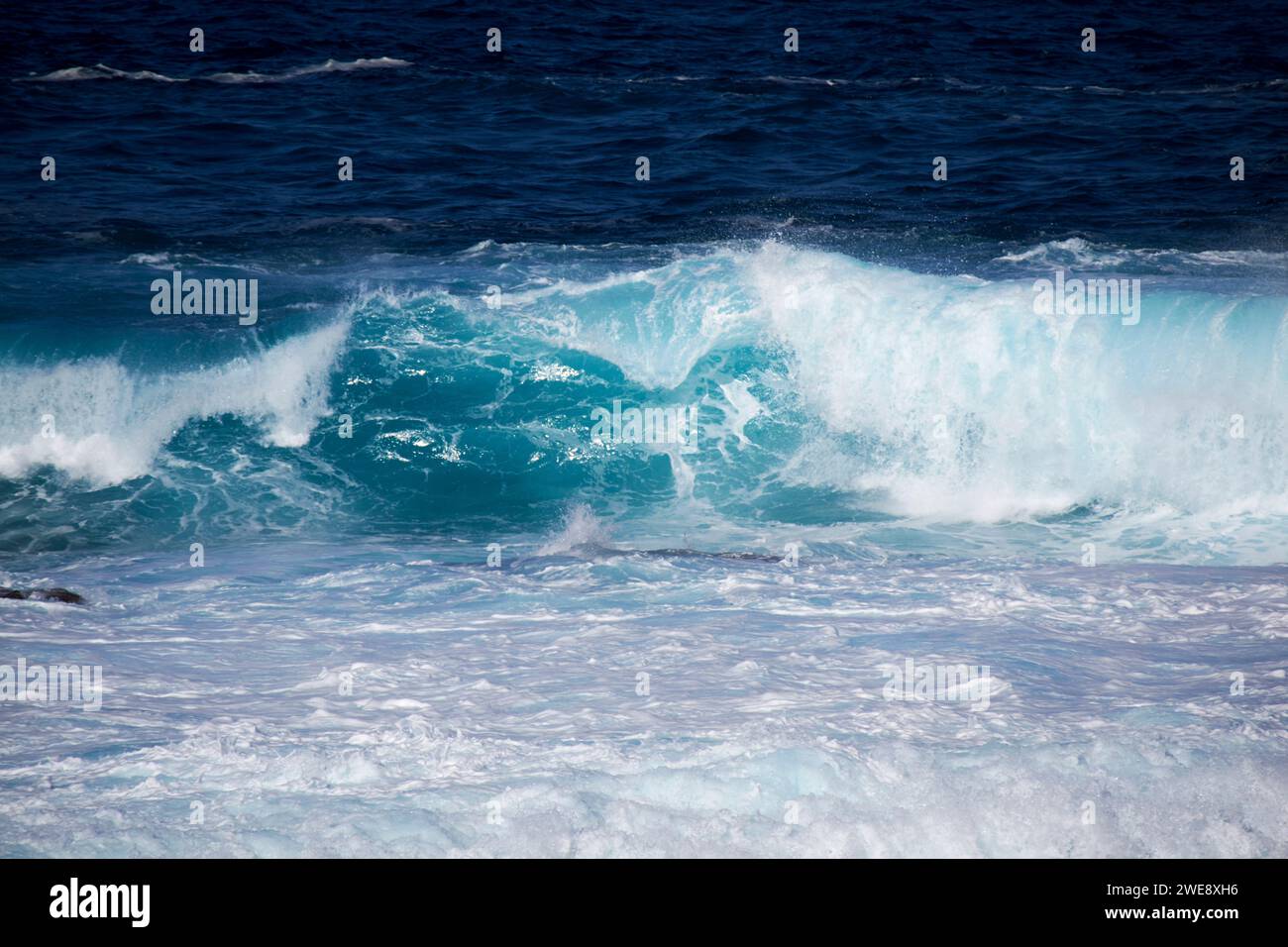 Blaue Meereswellen brechen über die flache felsige Küste an der atlantikküste der lanzarote kanarischen Inseln spanien Stockfoto