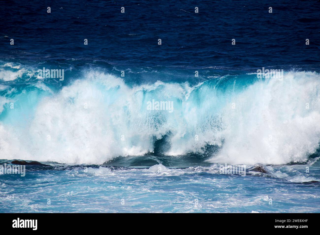 Blaue Meereswellen brechen über die flache felsige Küste an der atlantikküste der lanzarote kanarischen Inseln spanien Stockfoto