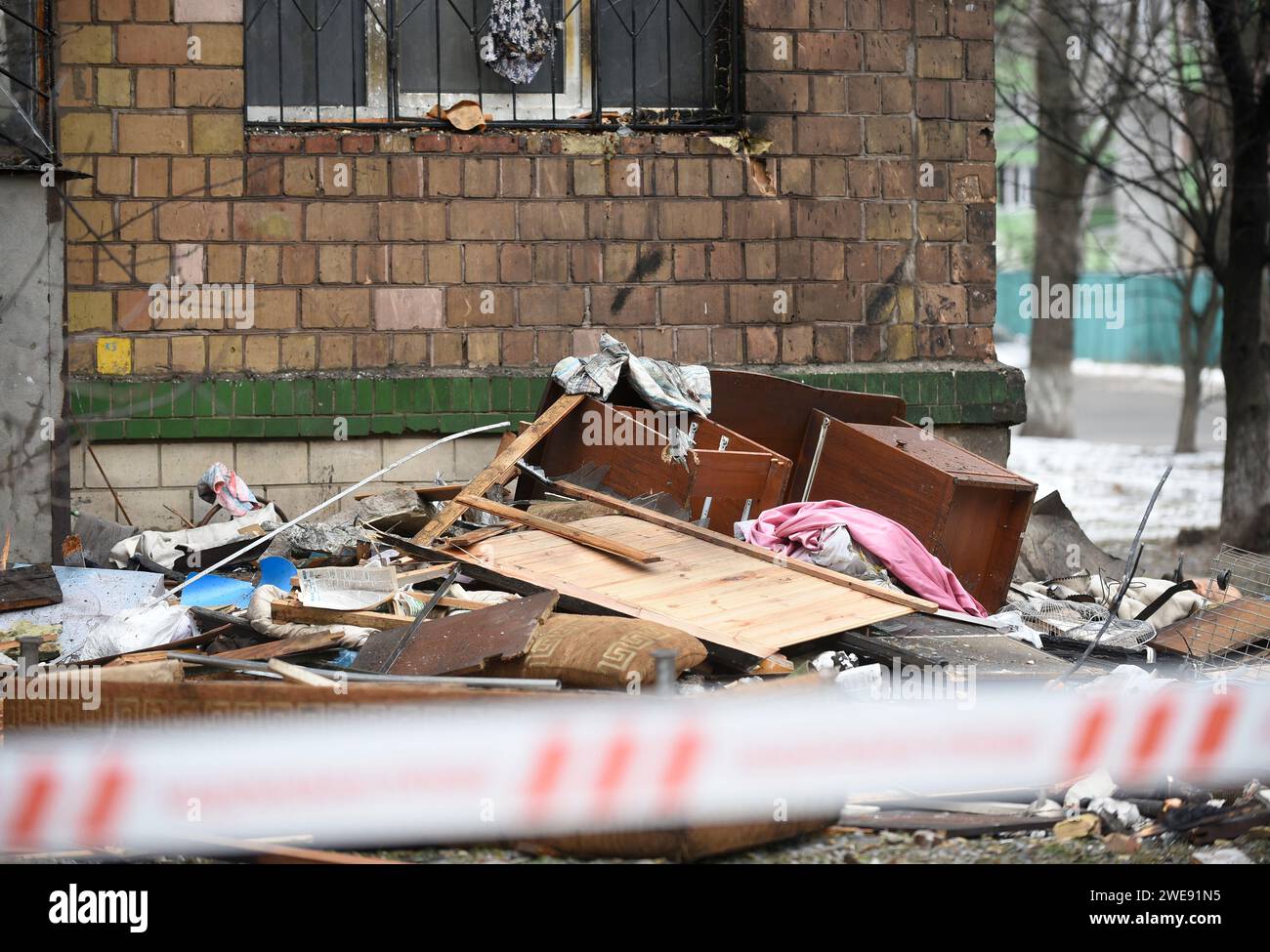 KIEW, UKRAINE - 23. JANUAR 2024 - kaputte Möbelstücke stapeln sich auf dem Boden vor einem Wohnblock im Bezirk Sviatoschynskyi, der beim russischen Raketenangriff am Dienstag Morgen, dem 23. Januar, in Kiew, Hauptstadt der Ukraine, beschädigt wurde. Stockfoto