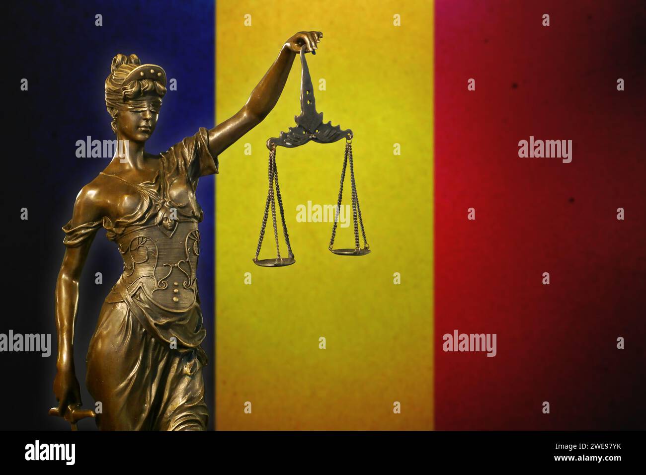 Nahaufnahme einer kleinen Bronzestatuette von Lady Justice vor einer Flagge des Tschad. Stockfoto