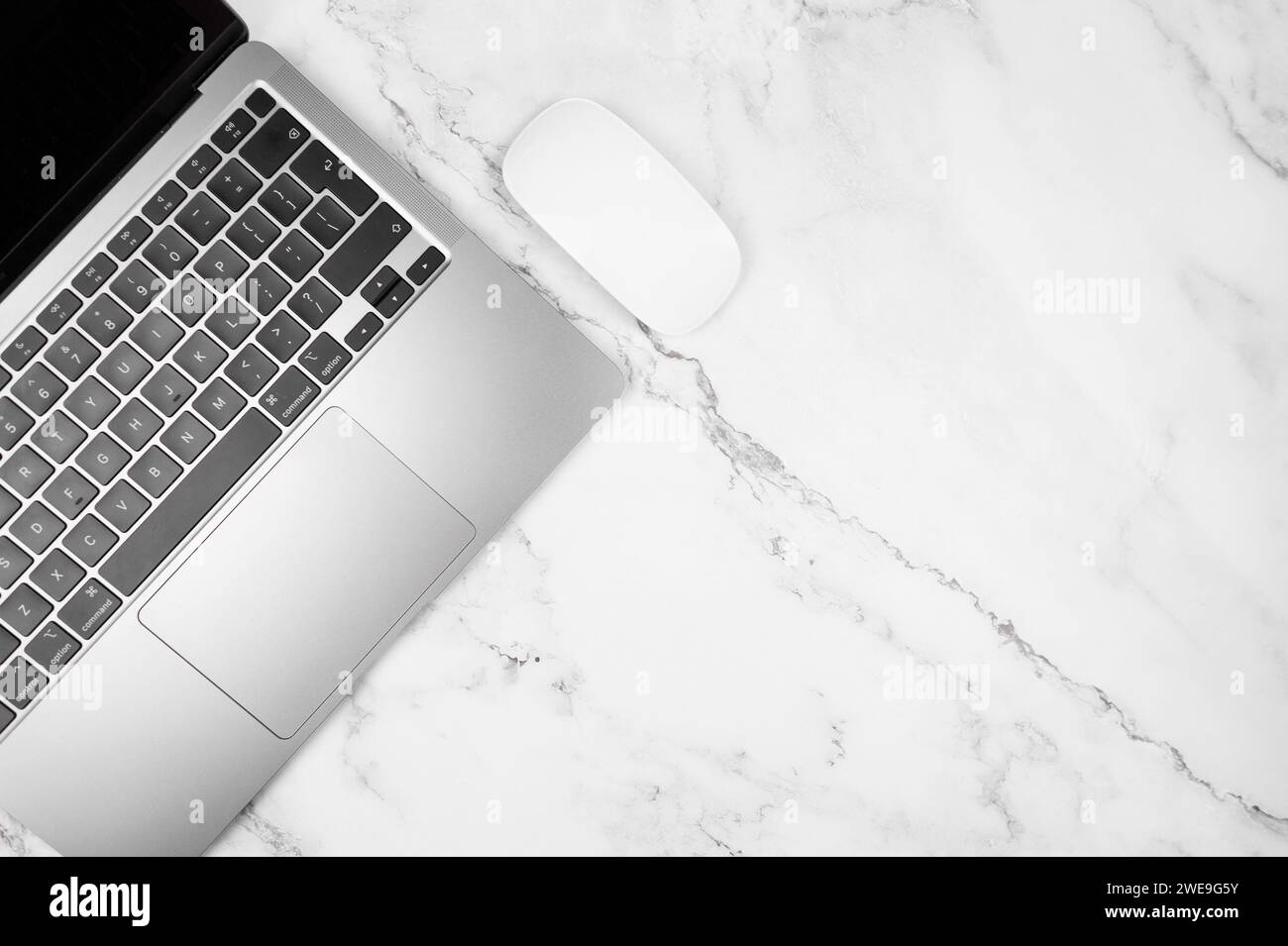 Blick von oben auf einen grauen Laptop auf weißem Marmorhintergrund. Bürotisch lat Lay, Kopierraum. Stockfoto