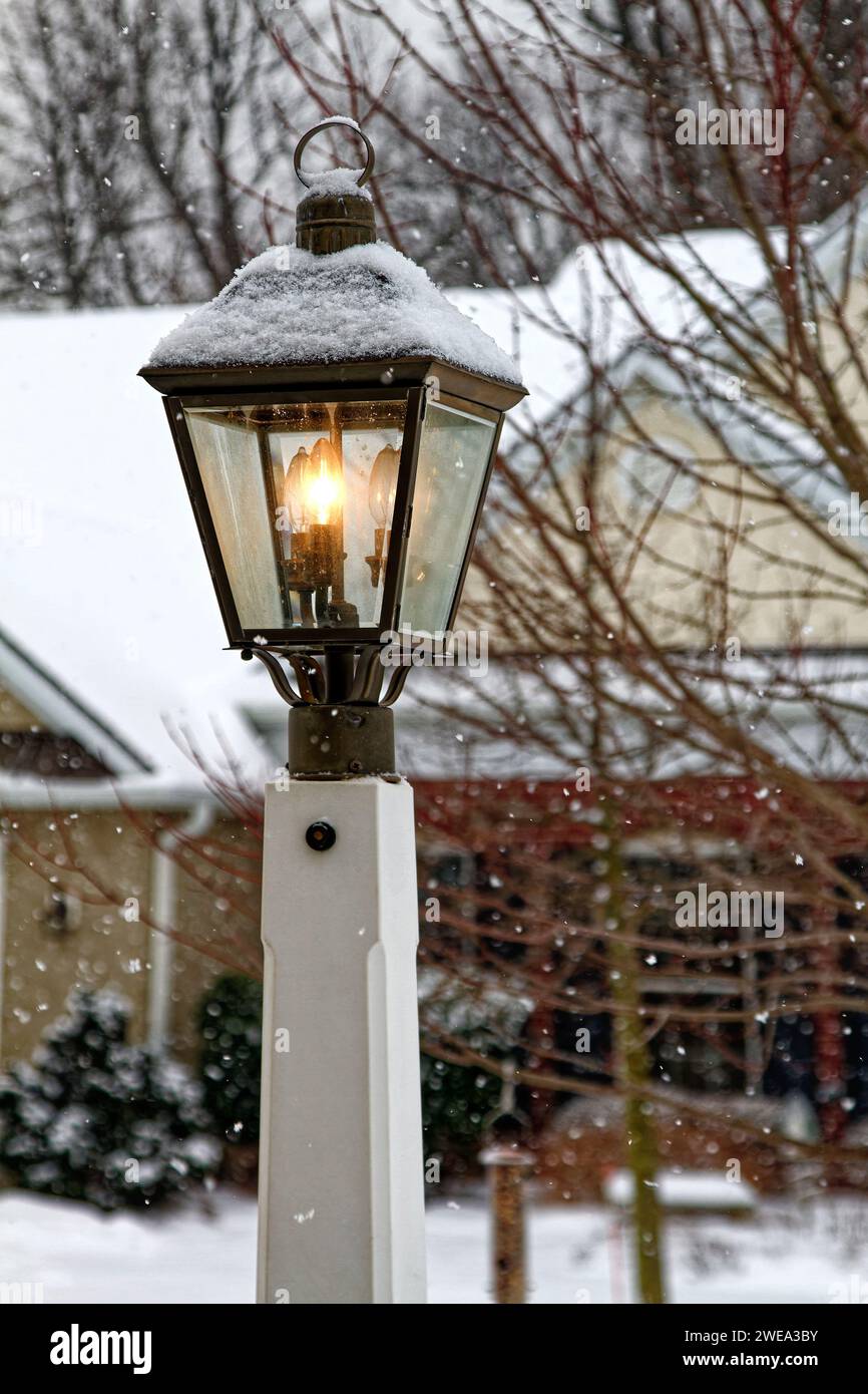 Lampenkreuz, beleuchtet, Bronzeoberteil, weißer Sockel, schneit, Schneekappe, Beleuchtung, flammenförmige Glühlampe, Wetterereignis, Winter, Pennsylvania Stockfoto