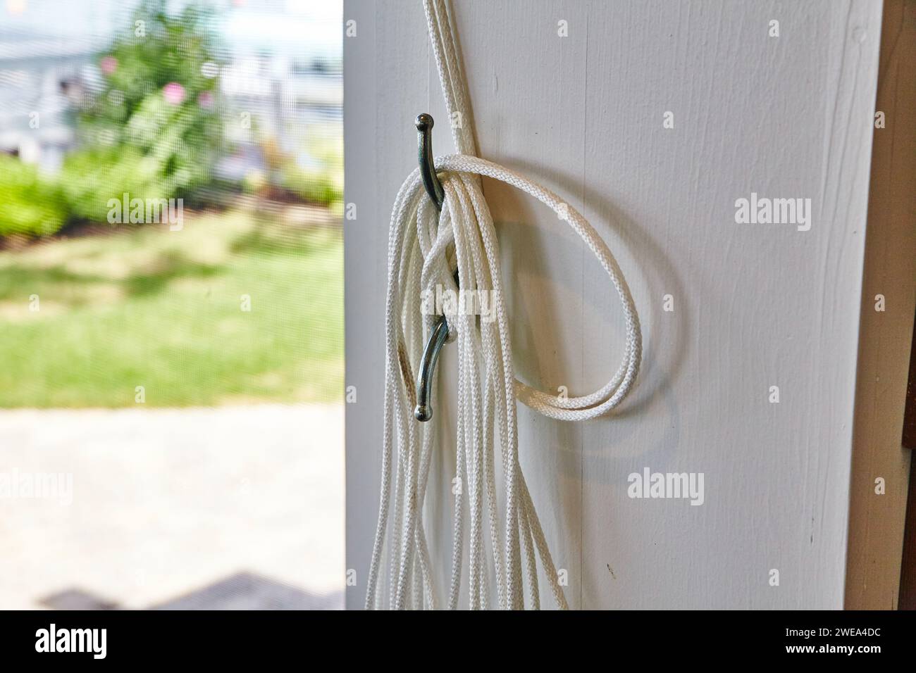 Weißes Seil am Türhaken im sonnigen Vorstadthaus Stockfoto