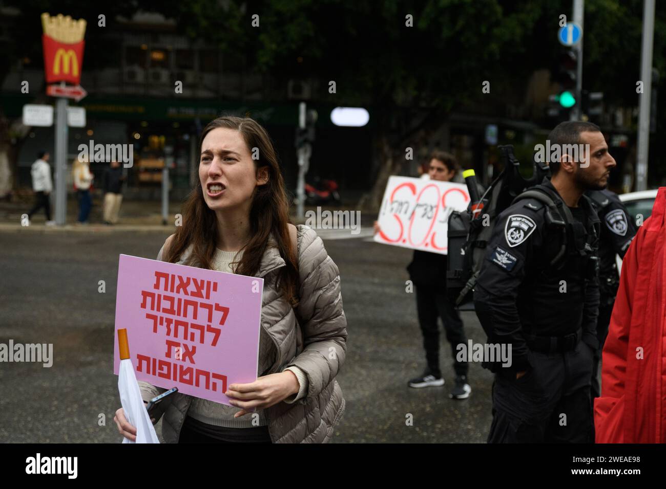 Eine israelische Frau hält ein Schild mit der Aufschrift „Frauen gehen auf die Straße, um die Geiseln zurückzubringen“, während sie während einer Demonstration in Tel Aviv eine Kreuzung blockiert, um eine sofortige Geiselnahme und einen Waffenstillstand zu fordern. 136 israelische Geiseln werden immer noch in lebensbedrohlicher Gefangenschaft der Hamas in Gaza festgehalten, nachdem sie während des Angriffs vom 7. Oktober als Geiseln genommen wurden. Tel Aviv, Israel. Januar 2024 (Matan Golan/SIPA USA). Stockfoto