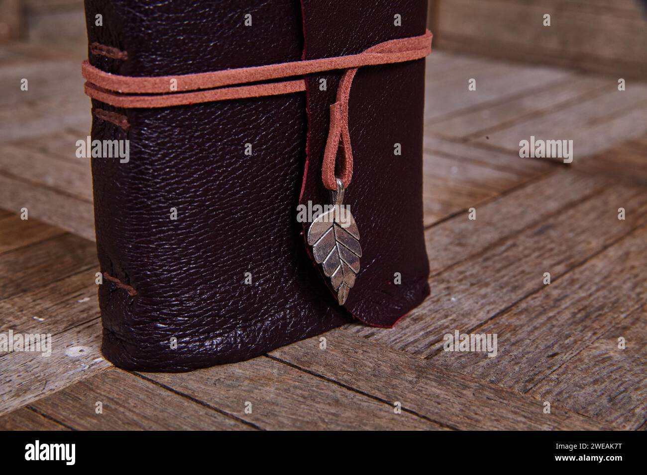 Handwerkliches Lederjournal mit Anhänger auf rustikalem Holz Stockfoto