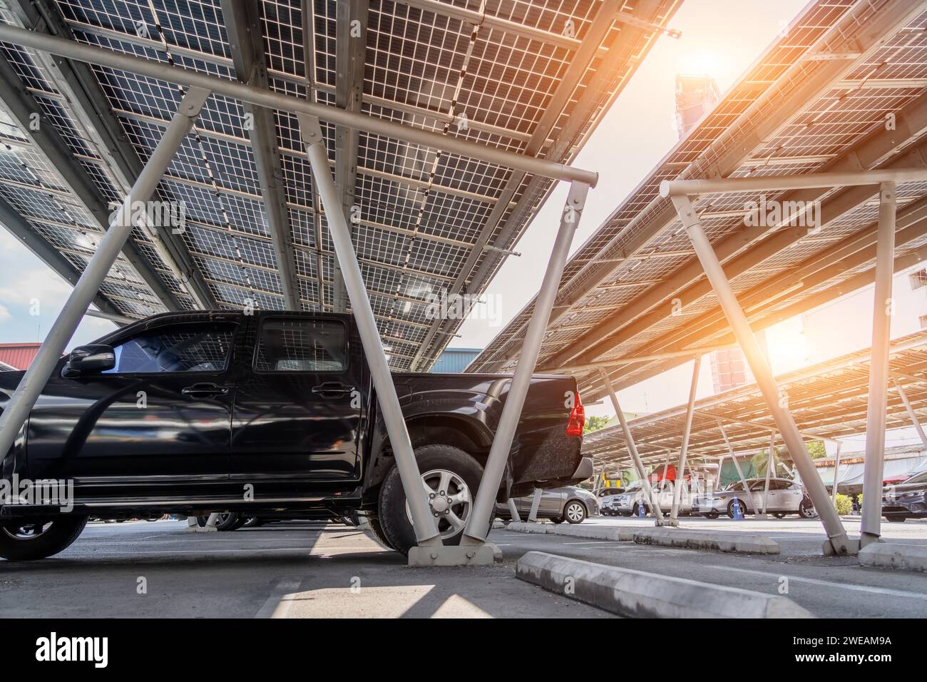 Parkplatz mit Vordach mit Solarpaneelen. Solarstromerzeugung. Schwarzes Pick-up-Fahrzeug mit Karosserie. Stockfoto