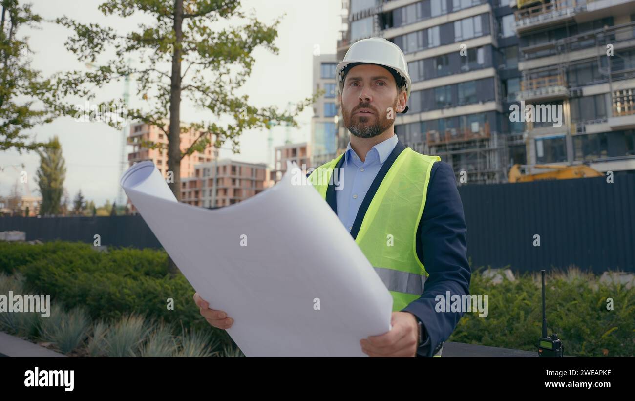 Nachdenklicher, nachdenklicher, verwirrter Arbeiter Reparaturmann in städtischem Stadtentwicklungsgebäude auf der Suche nach Bauplänen, männliche Architekturarchitektur Stockfoto