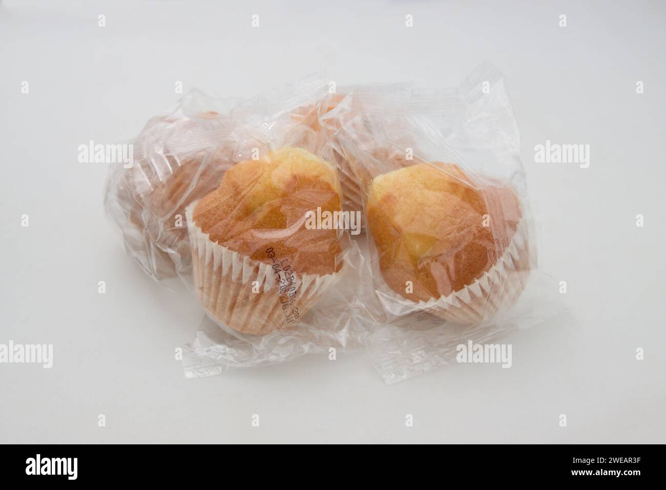 Nahaufnahme einiger industrieller Muffins, die in transparenten Kunststoff gewickelt sind, isoliert auf weißem Hintergrund Stockfoto