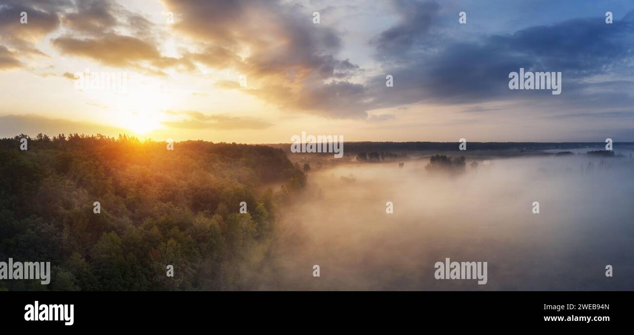 Traumhafter nebeliger Morgen auf einem Feld mit Wald vor dem Hintergrund eines bewölkten Himmels. Natur. Luftaufnahme. Stockfoto