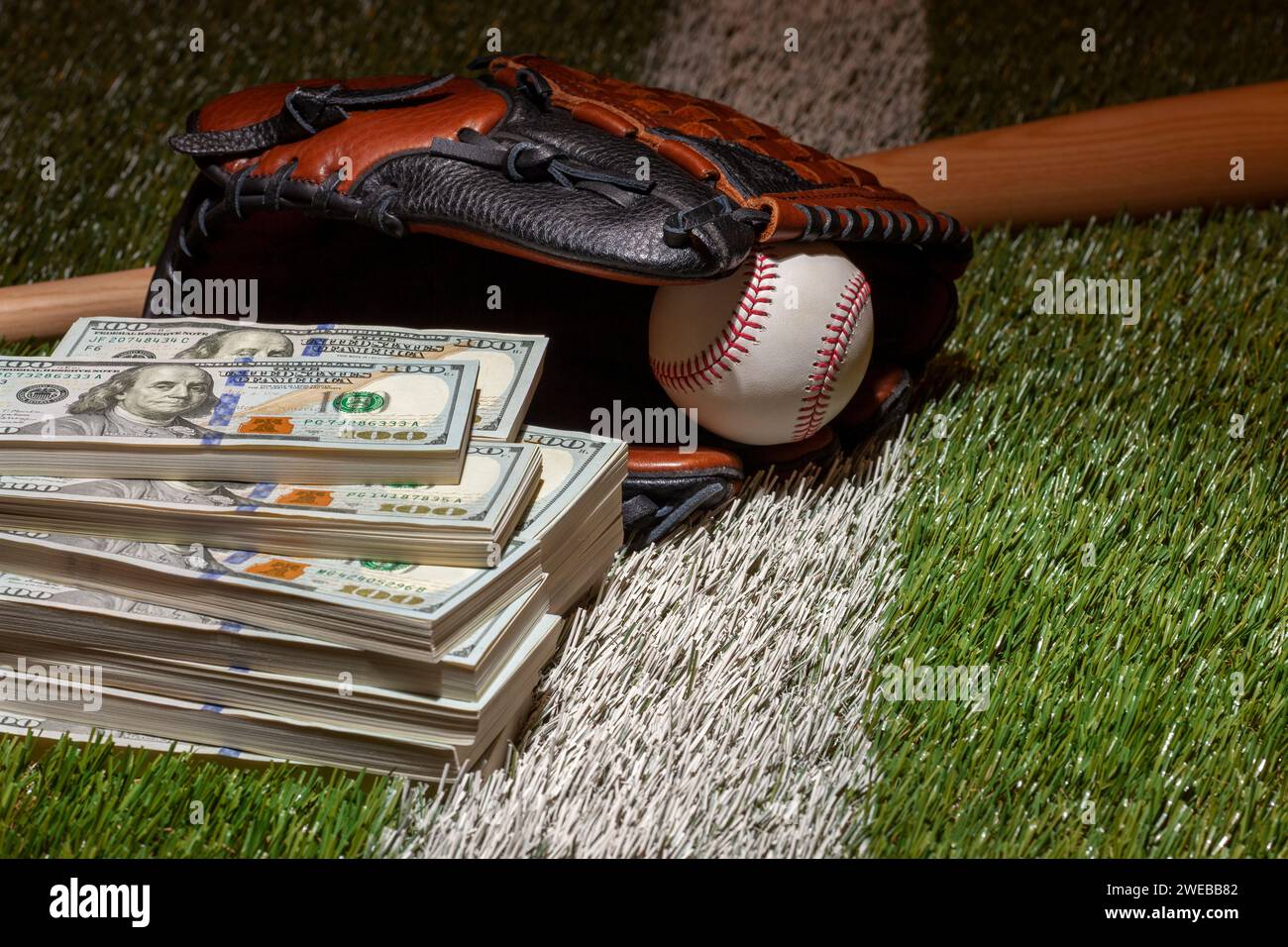 Baseball im Handschuh mit Schläger auf dem Grasfeld mit Hundert-Dollar-Scheinen Stockfoto