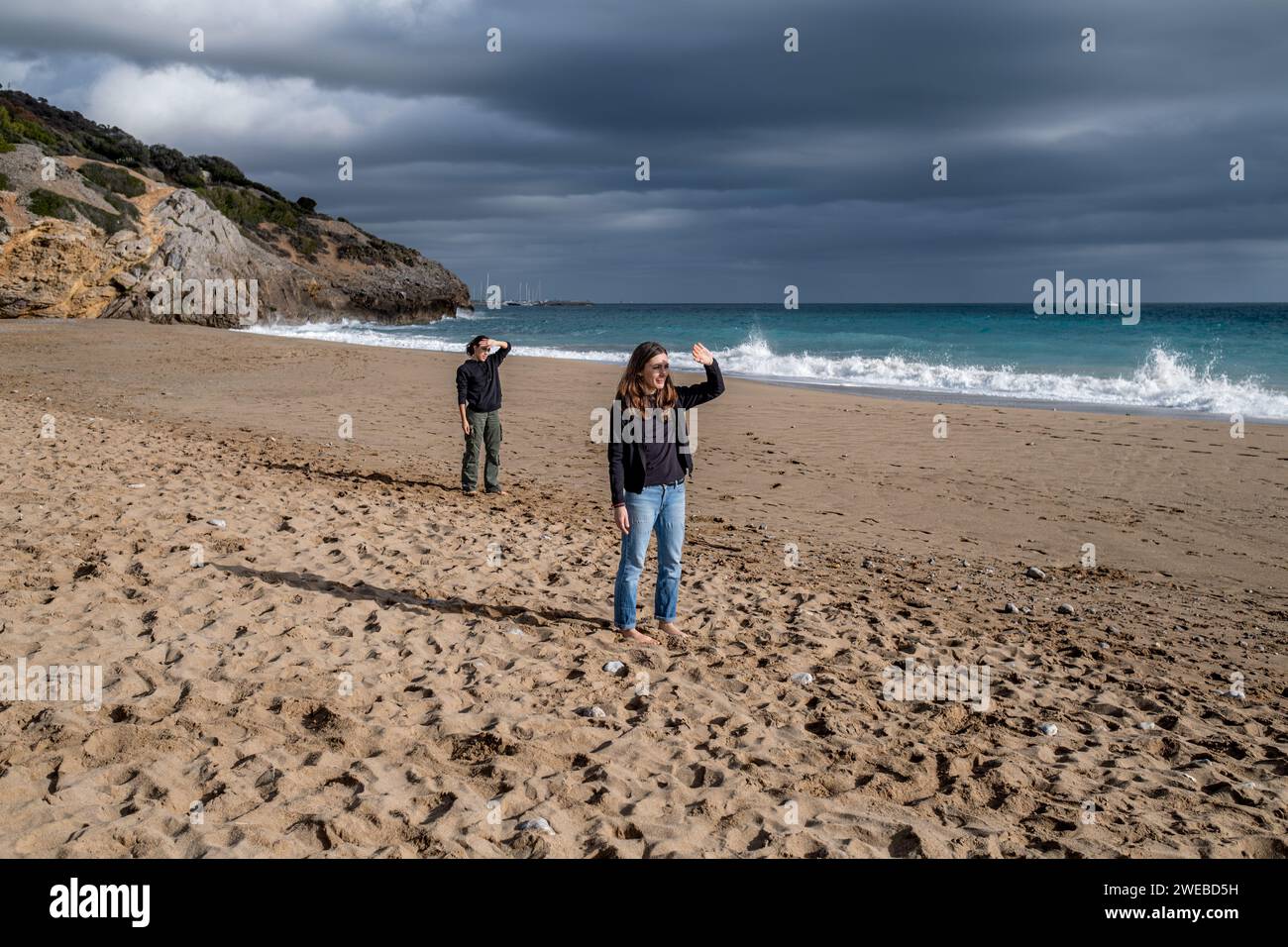 Zwei Frauen, die am Strand stehen und die gleiche Geste machen, um ihre Augen vor dem Sonnenlicht zu schützen. Junge Mutter und Tochter schützen ihre Augen. Stockfoto