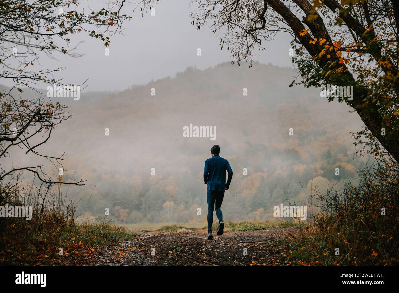 Die harmonische Verbindung eines jungen Trailläufers mit Foggy Autumn Stockfoto