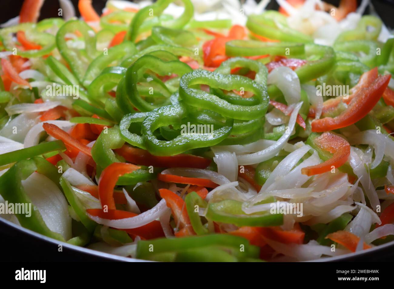 Nicht bearbeitetes Foto von gehackten, frisch geschnittenen, rohen grünen und roten Pfeffer mit Zwiebeln natürlicher Salat aus Bio-Produkten frischer Gartensalat. Stockfoto
