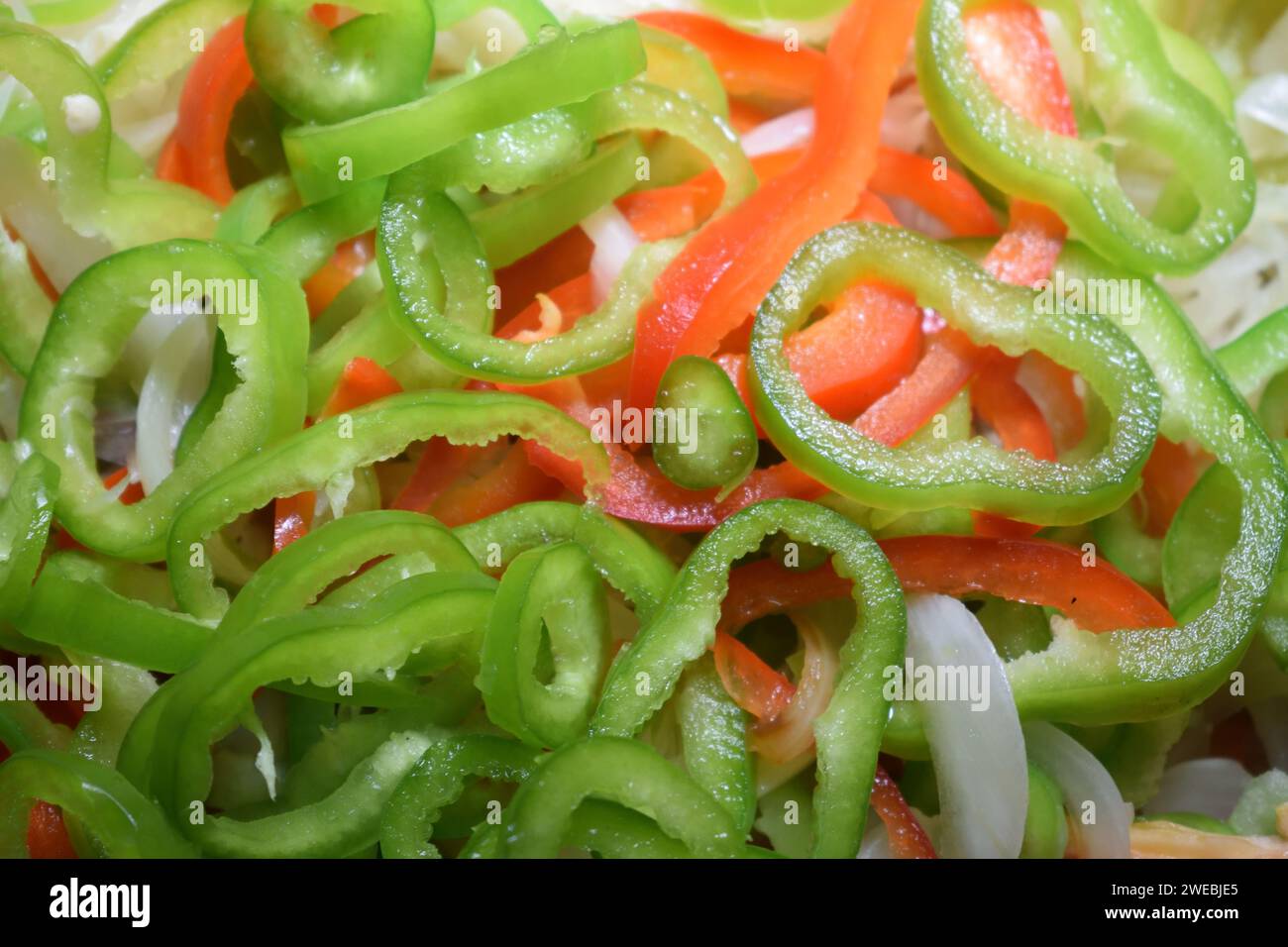 Nicht bearbeitetes Foto von gehackten, frisch geschnittenen, rohen grünen und roten Pfeffer mit Zwiebeln natürlicher Salat aus Bio-Produkten frischer Gartensalat. Stockfoto