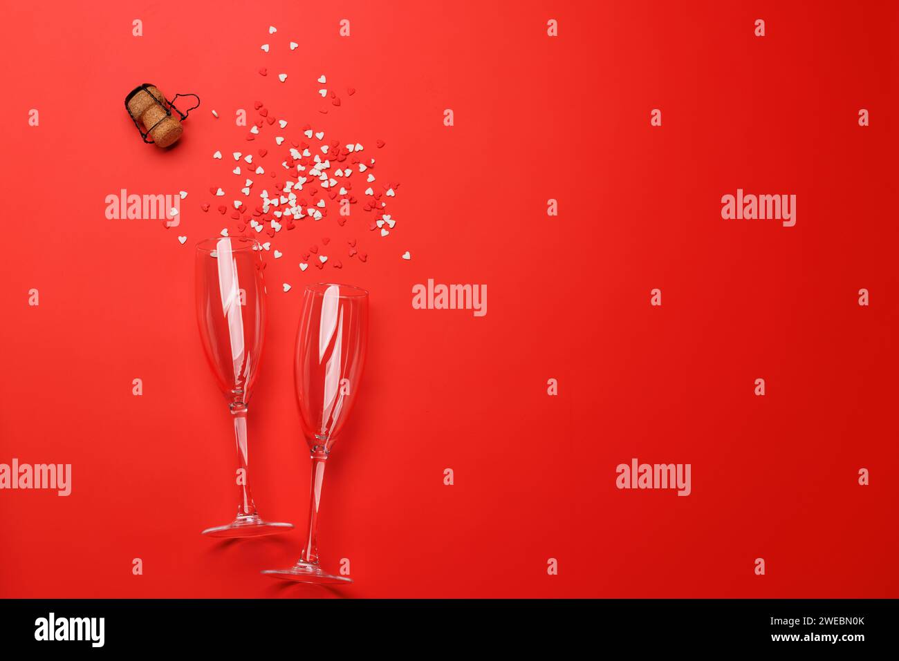 Valentinstag's Glitzer: Champagnergläser auf rotem Hintergrund, Grußkartenschablone. Flache Ladefläche mit Kopierraum Stockfoto