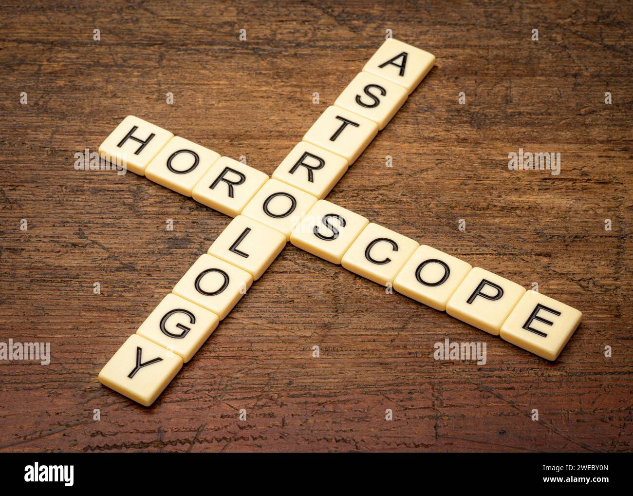 Astrologie und Horoskop-Kreuzworträtsel in Elfenbeinbuchstaben-Fliesen gegen rustikales verwittertes Holz Stockfoto