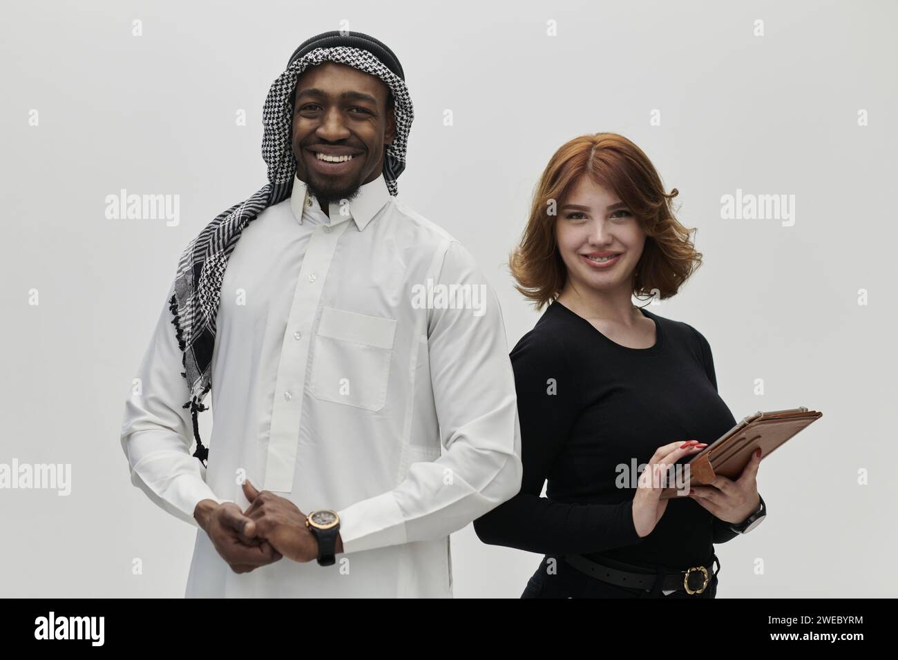 Eine arabische Unternehmerin und eine Geschäftsfrau, die Vertrauen und Einheit ausstrahlt, posieren vor einem klaren weißen Hintergrund und symbolisieren eine dynamische Partnerschaft Stockfoto