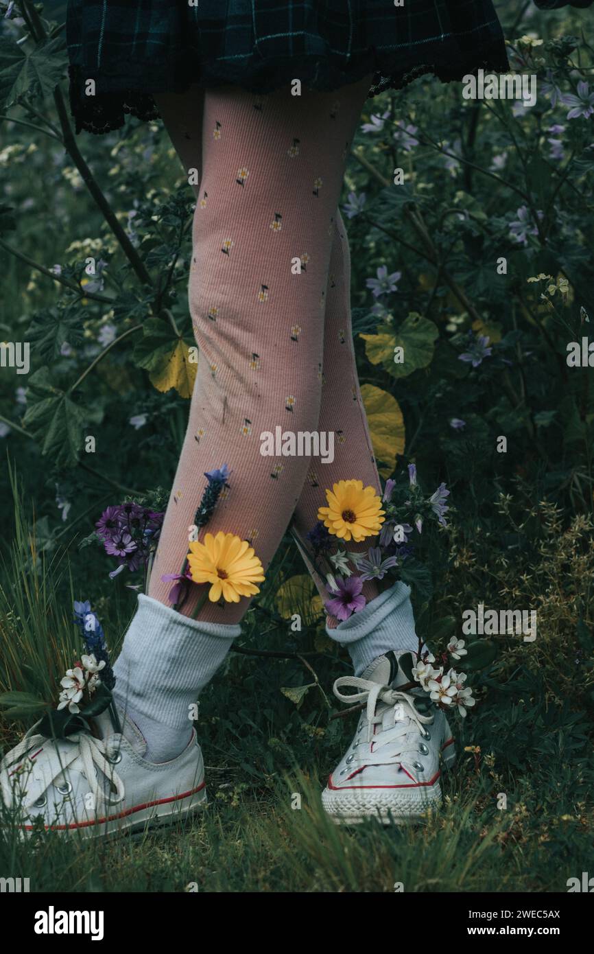 Skurrile Charaktere - Schwestern, die Hände halten und eine dumme Zeit mit hellen Blumen in den Schuhen haben - Pflanzen Kinder in der Natur, um zu wachsen. Stockfoto