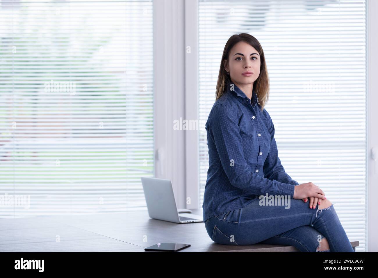 Der lässige, aber professionelle Look der Frau und der durchdachte Blick deuten auf strategisches Denken in einer entspannten Umgebung hin Stockfoto