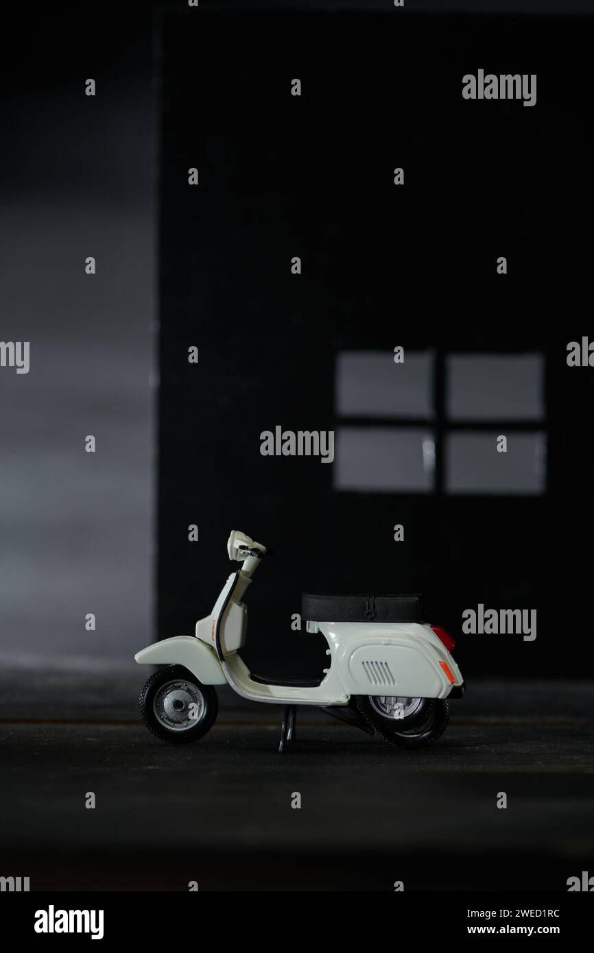 Foto einer alten Miniatur-Vespa, die auch Roller genannt wird. Fotografiert mit einem nicht so hellen Hintergrund, um das weiße Vespa-Objekt zu isolieren Stockfoto