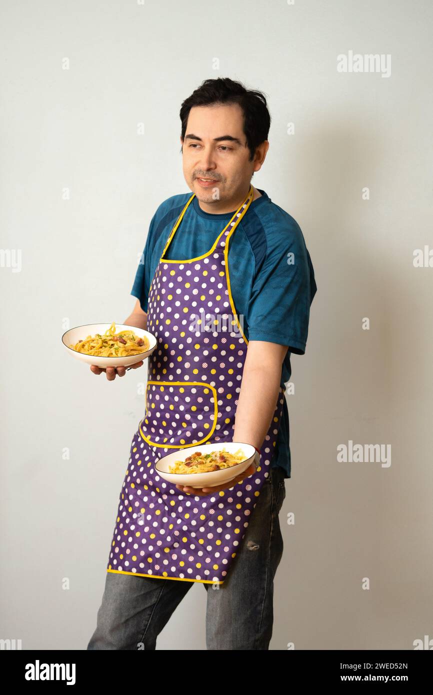 Ein Mann, der bereit ist, eine Mahlzeit mit zwei Tellern in der Hand zu servieren Stockfoto