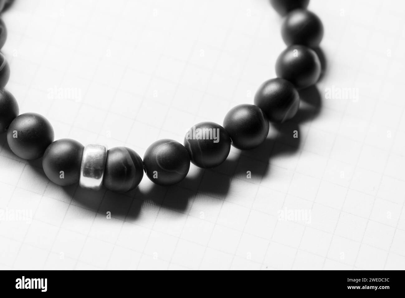 Armband aus schwarzen Achatperlen liegt auf weißem Hintergrund, Nahaufnahme mit selektivem Weichfokus Stockfoto