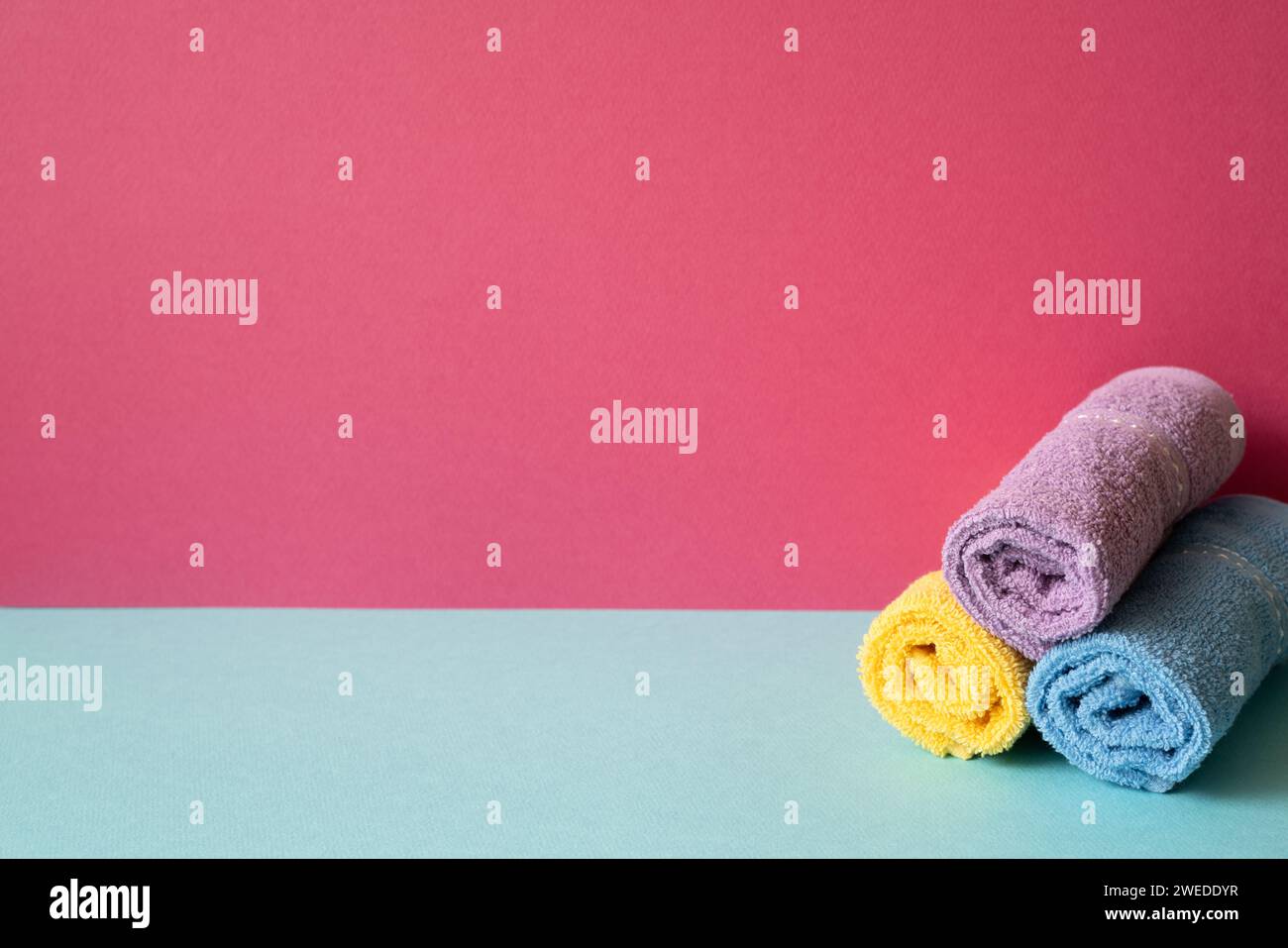 Stapel Duschtücher im Badezimmer auf himmelblauem Regal. Pinkfarbener Wandhintergrund Stockfoto