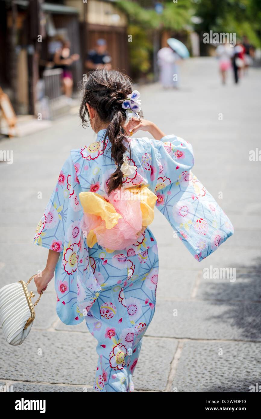 Japanisches Mädchen in einem Kimono Yukata, das auf der Steinstraße in Kyoto, Japan, läuft. Stockfoto