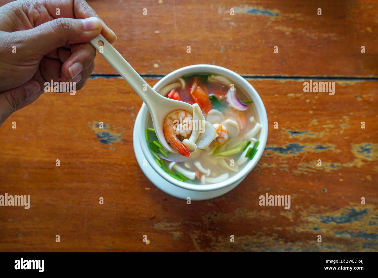 Schüssel mit Meeresfrüchten von Tom Yum Kung von oben auf Holztisch. Thailändische scharfe und saure klare Suppe mit Garnelen und Meeresfrüchten. Asiatisches Essen. Garnelen in scharfer Suppe, Tom y Stockfoto