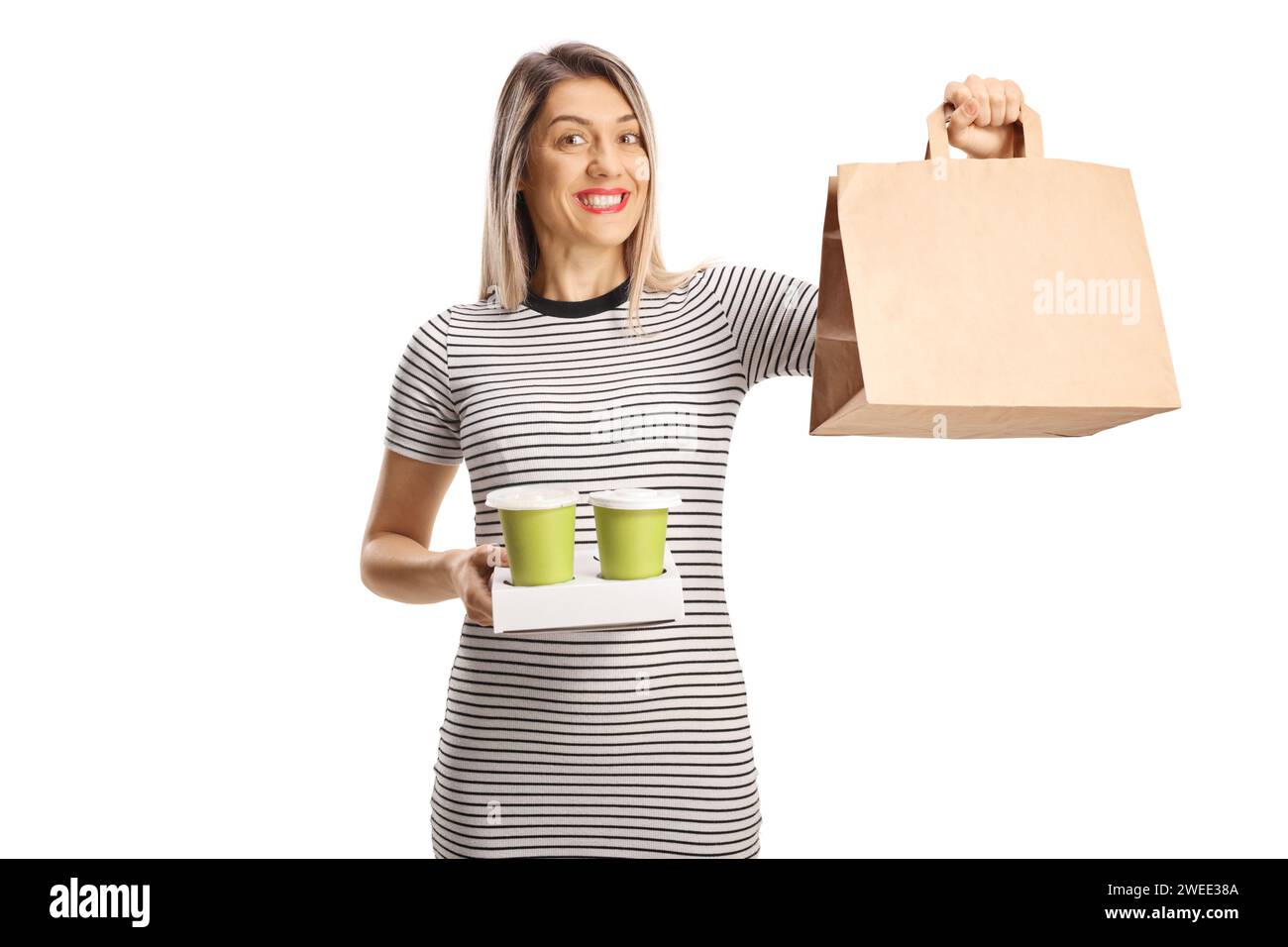 Glückliche junge Frau, die Essensbeutel und Kaffee auf weißem Hintergrund hält Stockfoto