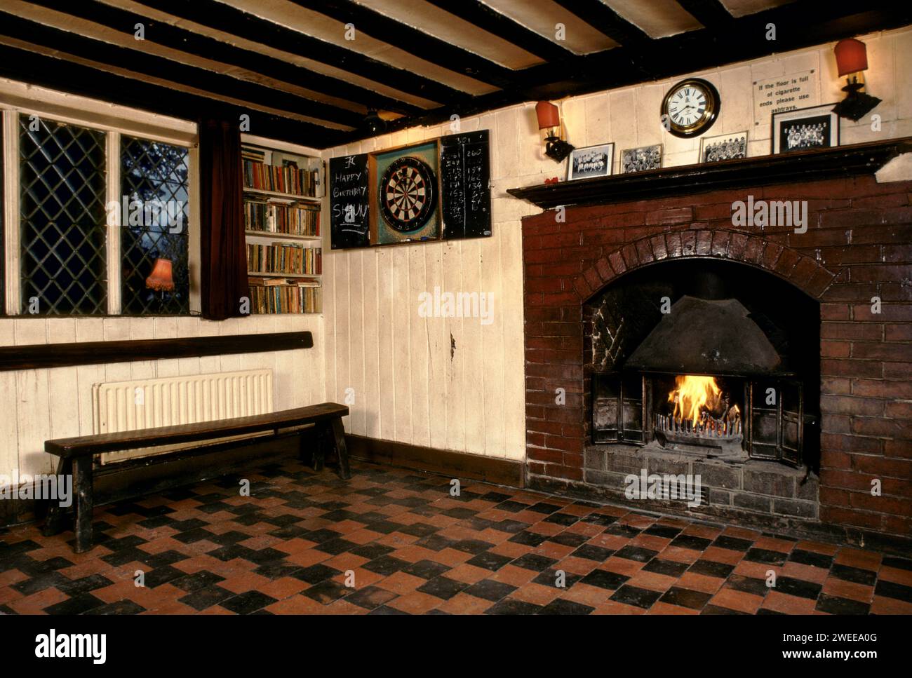 Das Schloss, das Dorf Pub in Chiddingstone, Kent. Innenraum mit Dartbrett und echtem Holzfeuer. Fliesenboden, Holzbank. 1990ER 1991 UK HOMER SYKES Stockfoto