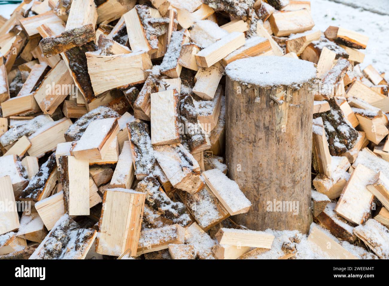 Eine Axt zum Spalten von Brennholz, in einen Baumstamm gesteckt, um Holz zu hacken. Stockfoto