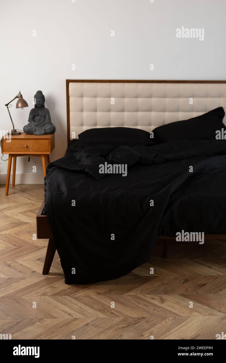 Die Textur der schwarzen, zerknitterten Bettwäsche auf dem Bett Stockfoto