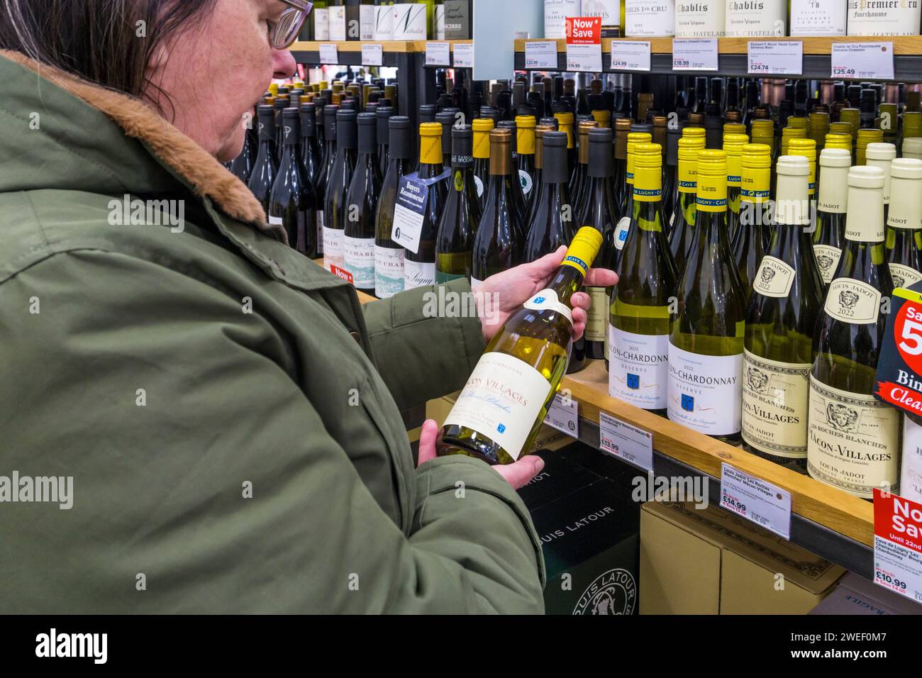 Frau, die eine Flasche französischen Macon-Dörfer in einem Majestic Wine off-Licence in Betracht zieht. Stockfoto