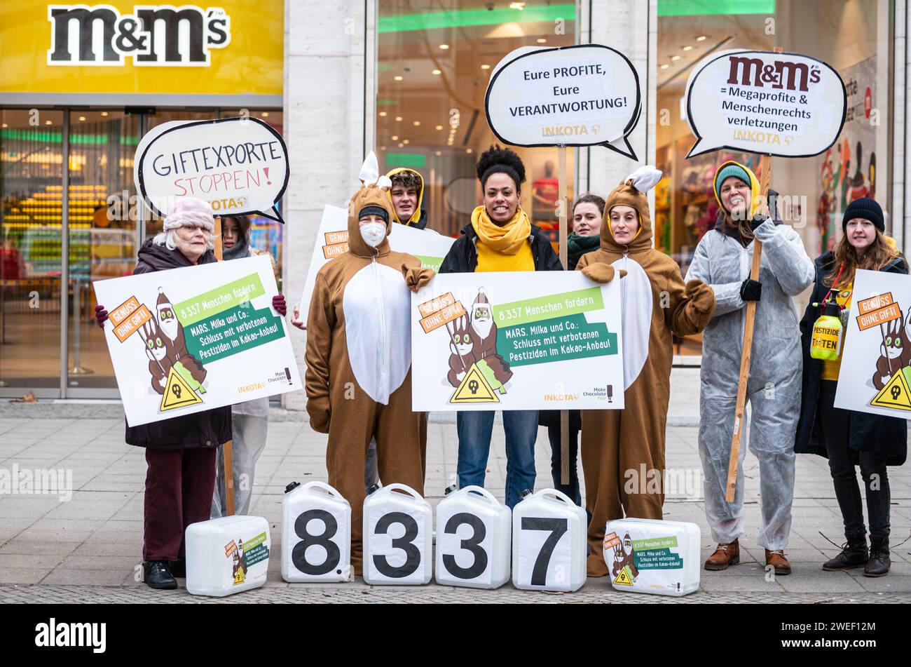 Deutschland, Berlin, 25. Januar 2024: Aktivistinnen und Aktivistinnen protestieren gegen den Einsatz hochgefährlicher Pestizide im Kakaoanbau im Vorfeld der ISM Cologne 2024 vor dem MARS M&M Store Berlin. Die Aktivisten und Unterstützer der Entwicklungsorganisation INKOTA-netzwerk e.V. fordern große Schokoladenunternehmen wie MARS AUF, den Einsatz hochgefährlicher Pestizide in ihren Lieferketten einzustellen, die in Europa aufgrund ihrer schädlichen Auswirkungen nicht zugelassen sind. Sie weisen darauf hin, dass 1,5 Millionen Kinder diesen Pestiziden in Kakaokulturen ausgesetzt sind Stockfoto