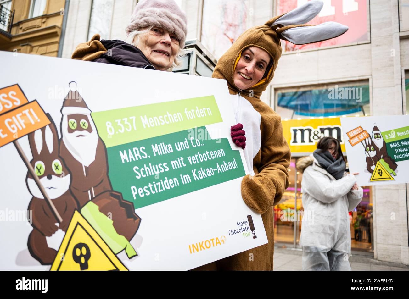 Berlin, Berlin, Deutschland. Januar 2024. Aktivistinnen und Aktivistinnen protestieren gegen den Einsatz hochgefährlicher Pestizide im Kakaoanbau im Vorfeld der ISM Cologne 2024 vor dem MARS M&M Store Berlin. Die Aktivisten und Unterstützer der Entwicklungsorganisation INKOTA-netzwerk e.V. fordern große Schokoladenunternehmen wie MARS AUF, den Einsatz hochgefährlicher Pestizide in ihren Lieferketten einzustellen, die in Europa aufgrund ihrer schädlichen Auswirkungen nicht zugelassen sind. Sie weisen darauf hin, dass 1,5 Millionen Kinder diesen Pestiziden in Kakao C ausgesetzt sind Stockfoto