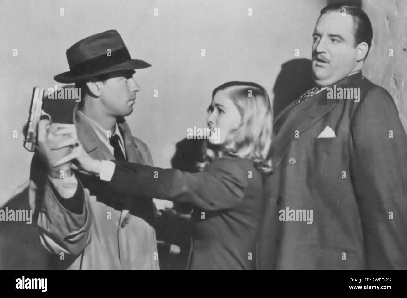 Alan Ladd und Veronica Lake spielen in „This Gun for Hire“ (1942), einem packenden Film Noir. Ladd stellt Philip Raven dar, einen geschickten Auftragskiller, während Lake Ellen Graham spielt, eine Nachtclub-Sängerin und Geheimagentin. Die Handlung entfaltet sich, als Raven sich in eine gefährliche Spionage mit Graham verstrickt, was zu spannenden Wendungen führt. Stockfoto