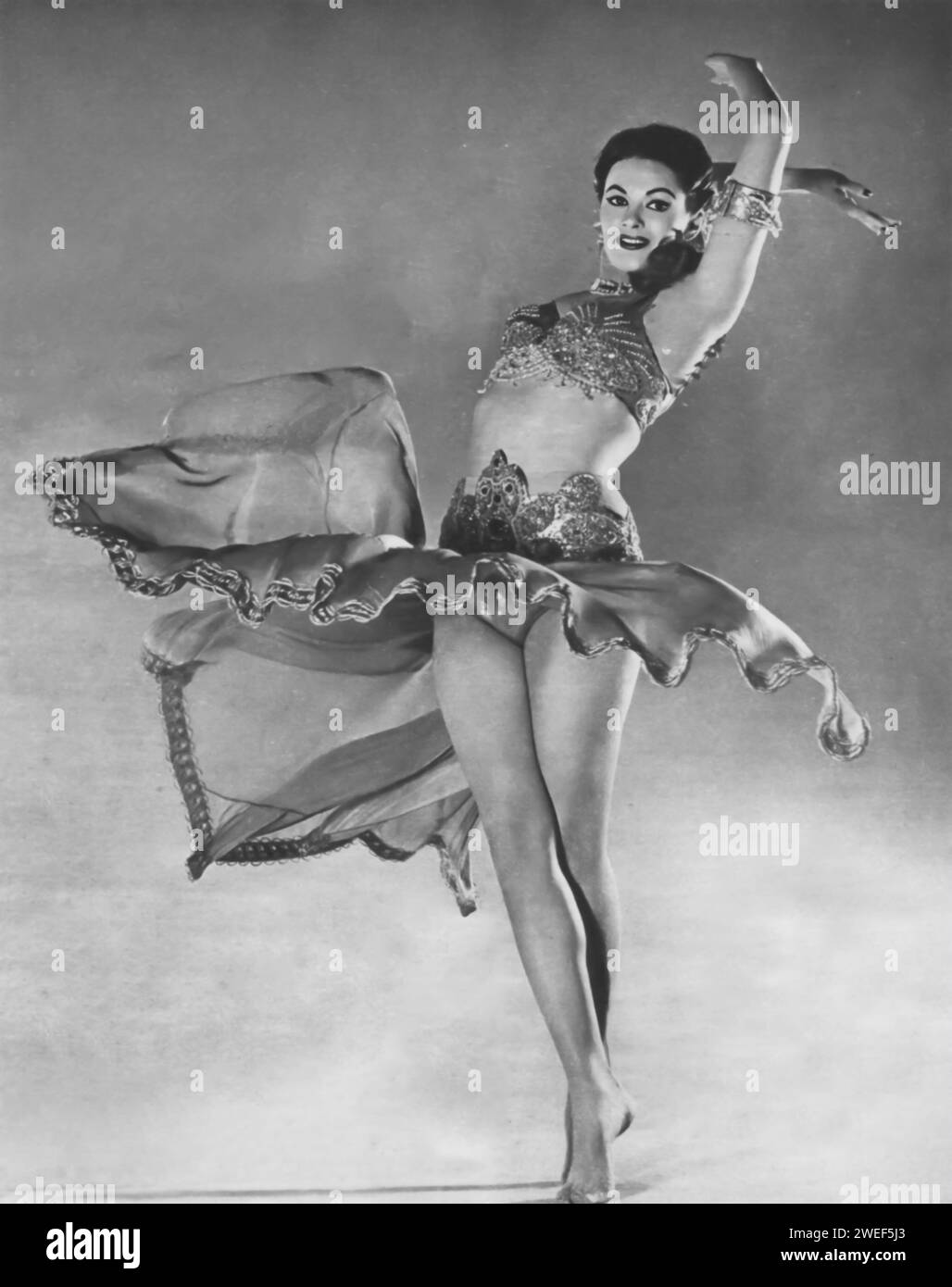 Star und Schauspielerin Yvonne de Carlo tanzt in einer Szene aus dem Film „Hotel Sahara“ (1951). In dieser Komödie spielt de Carlo Yasmin Pallas, eine bezaubernde Kabarettttänzerin, deren Hotel in der nordafrikanischen Wüste zu einem unwahrscheinlichen Knotenpunkt für verschiedene Fraktionen des Zweiten Weltkriegs wird. Stockfoto